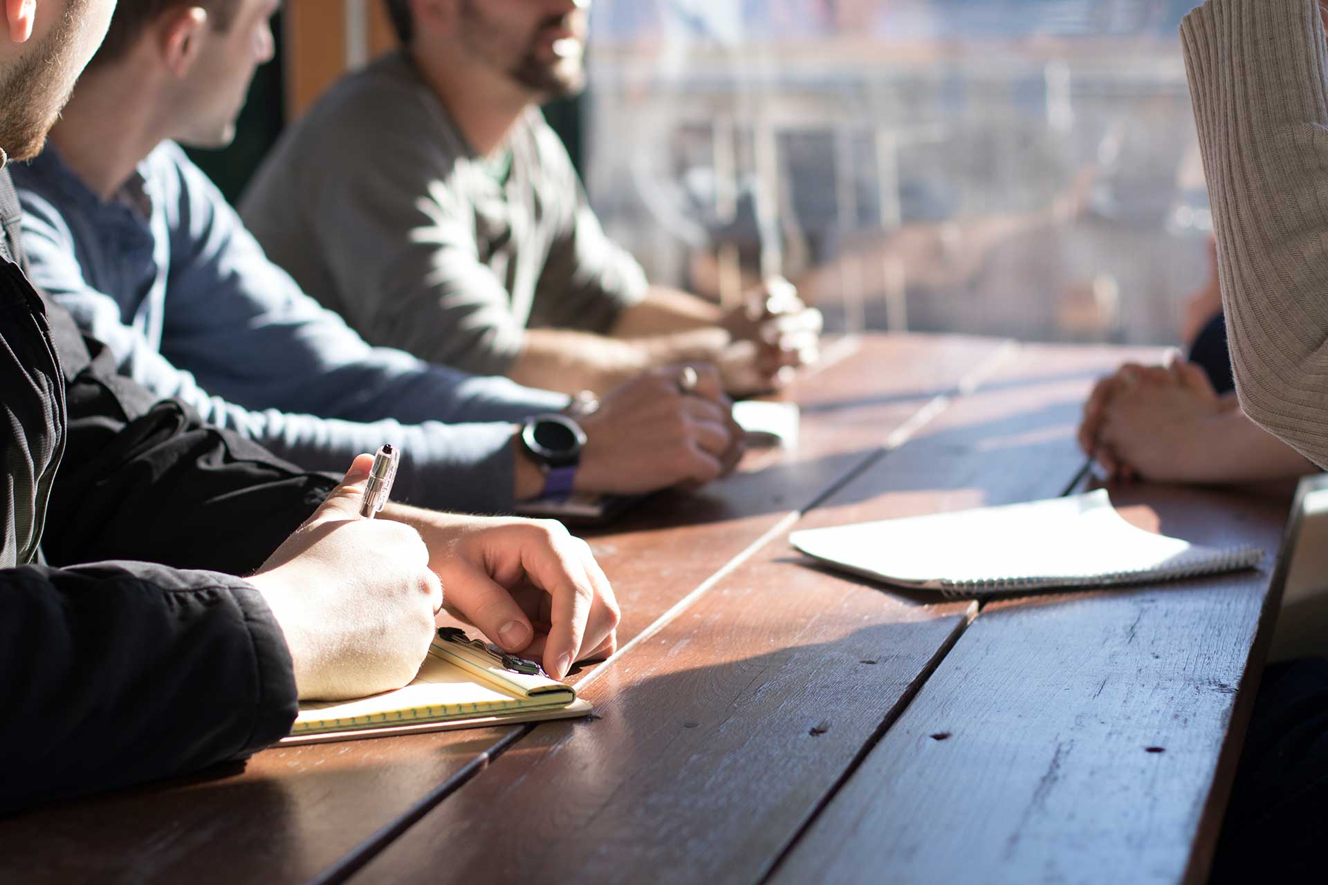 group-of-people-in-a-meeting Hands on a meeting table